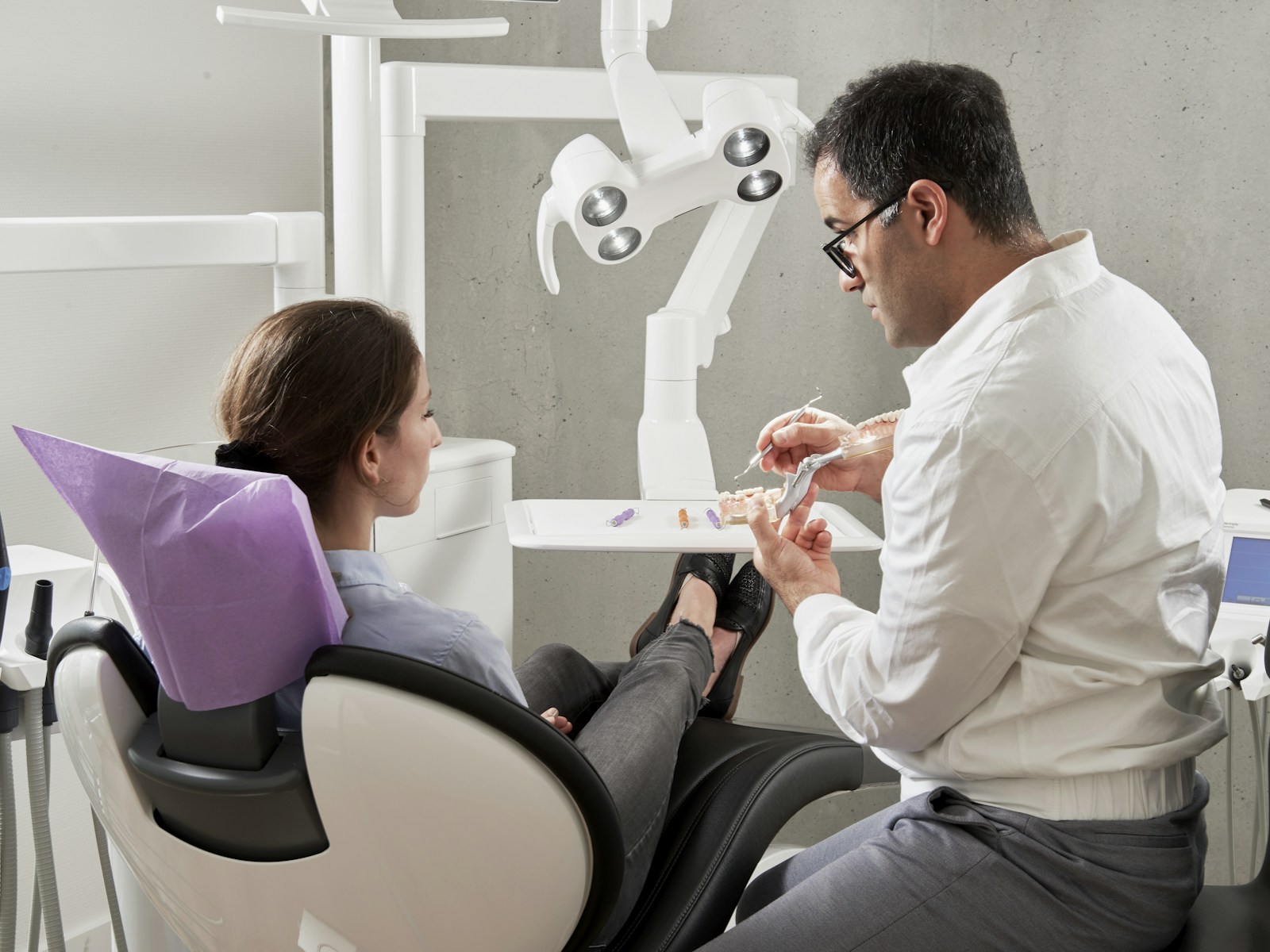 Dentista explicando o tratamento a uma paciente sentada na cadeira
